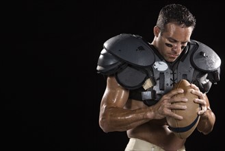 Football player wearing protective gear and holding football. Date: 2008