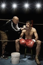 Coach wiping boxer with sponge in corner of boxing ring. Date : 2008