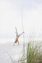 Boy doing cartwheel on beach. Date : 2008