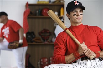 Baseball player holding bat in locker room. Date: 2008