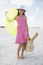 Portrait of girl holding inflatable tube and bag on beach. Date : 2008