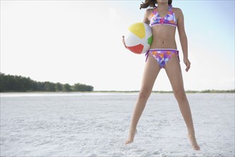 Girl in bikini jumping with beach ball. Date: 2008