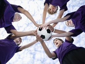 Boys holding soccer ball in huddle. Date : 2008