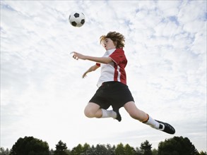 Boy jumping toward soccer ball in mid-air. Date: 2008