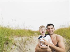 Portrait of father and son hugging on beach. Date: 2008