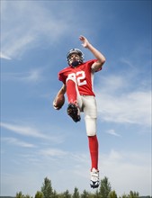 Football player in mid-air holding football. Date: 2008