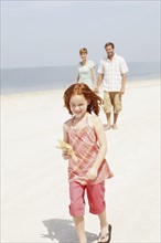 Couple and daughter walking on beach. Date : 2008
