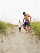 Father and son holding hands and running on beach. Date: 2008