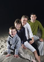Portrait of family sitting on driftwood at beach. Date: 2008