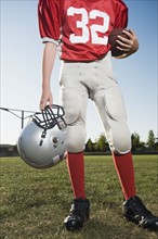 Football player holding helmet and football on field. Date : 2008