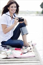 Woman with camera sitting on dock. Date : 2008