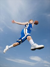 Teenage basketball player in mid-air with basketball. Date: 2008
