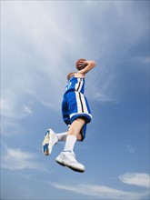 Teenage basketball player in mid-air shooting basketball. Date: 2008