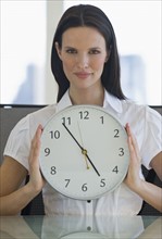 Portrait of businesswoman holding clock.