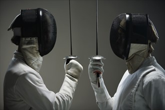 Fencers in masks facing off with fencing foils. Date : 2008