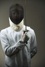 Portrait of fencer in uniform and mask holding fencing foil. Date: 2008