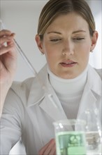 Close up of scientist extracting liquid from beaker.