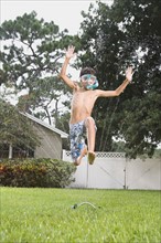Boy with snorkeling mask running through sprinkler. Date : 2008