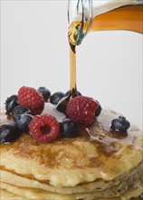 Close up of maple syrup being poured on pancakes.