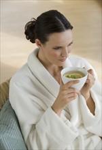 Woman in bathrobe drinking tea.