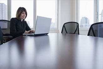 Businesswoman using laptop in conference room.