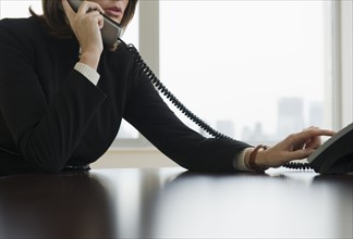 Woman dialing telephone in office.