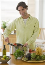 Portrait of man preparing meal in kitchen.