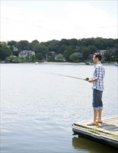 Man fishing off dock with beer at feet. Date: 2008