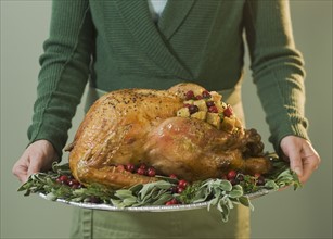 Man holding Thanksgiving turkey on decorated platter.