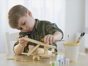 Boy building wooden airplane model.