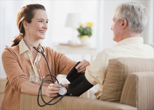 Nurse taking senior man’s blood pressure.