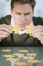 Businessman looking at puzzle pieces.