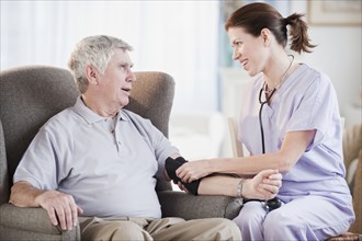 Nurse taking senior man’s blood pressure.