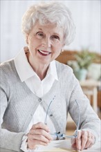 Portrait of senior woman sitting at table.