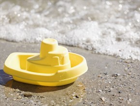 Toy boat on beach. Photographe : Jamie Grill