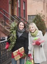 Women carrying Christmas gifts on urban street. Photographe : Jamie Grill