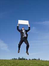 Businessman jumping with blank sign.