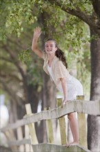 Girl standing on fence waving. Photographe : mark edward atkinson