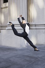 Businesswoman dancing on urban sidewalk. Photographe : PT Images