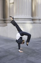 Businesswoman dancing on urban sidewalk. Photographe : PT Images