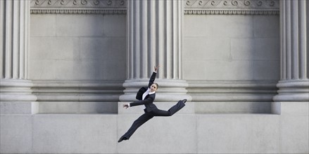 Businesswoman dancing in urban setting. Photographe : PT Images