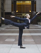 Businesswoman dancing in urban setting. Photographe : PT Images