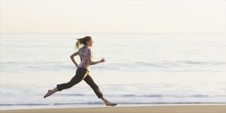 Woman running on beach. Photographe : PT Images