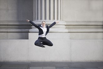 Businesswoman dancing in urban setting. Photographe : PT Images