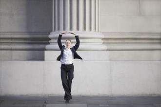 Businesswoman dancing in urban setting. Photographe : PT Images