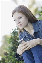 Young woman listening to mp3 player. Photographe : PT Images