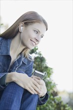 Young woman listening to mp3 player. Photographe : PT Images