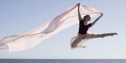 Dancer leaping on beach. Photographe : PT Images