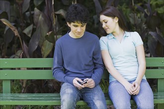 Young couple sitting on park bench. Photographe : PT Images