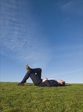 Businessman laying in grass.